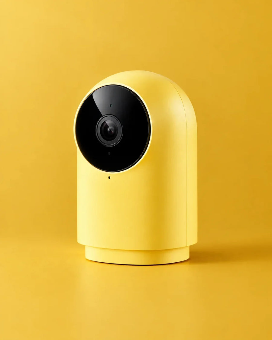 Modern yellow smart security camera with a black circular lens on a yellow background.