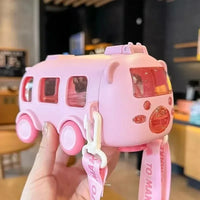 Pink toy bus held by a hand with a blurred indoor background