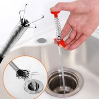 Flexible four-claw drain snake tool being inserted into a clogged kitchen sink pipeline layout