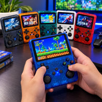 A person holds a translucent blue retro handheld gaming console in front of a desk with five other console colors in the background, including black, orange, green, white, and red. Screens show classic gaming interfaces.