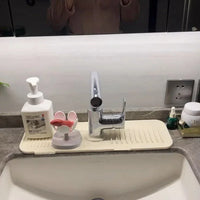Washing sponge and a glass soap dispenser arranged neatly on top of the faucet drain mat ridges