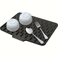 Black rubber mat with white cups and silverware on a white background