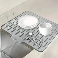 Gray silicone mat with dishes and cutlery on a kitchen counter