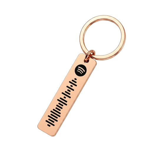 A rose gold keychain featuring a rectangular bar engraved with a Spotify logo and sound wave, attached to a split key ring on a solid white background.